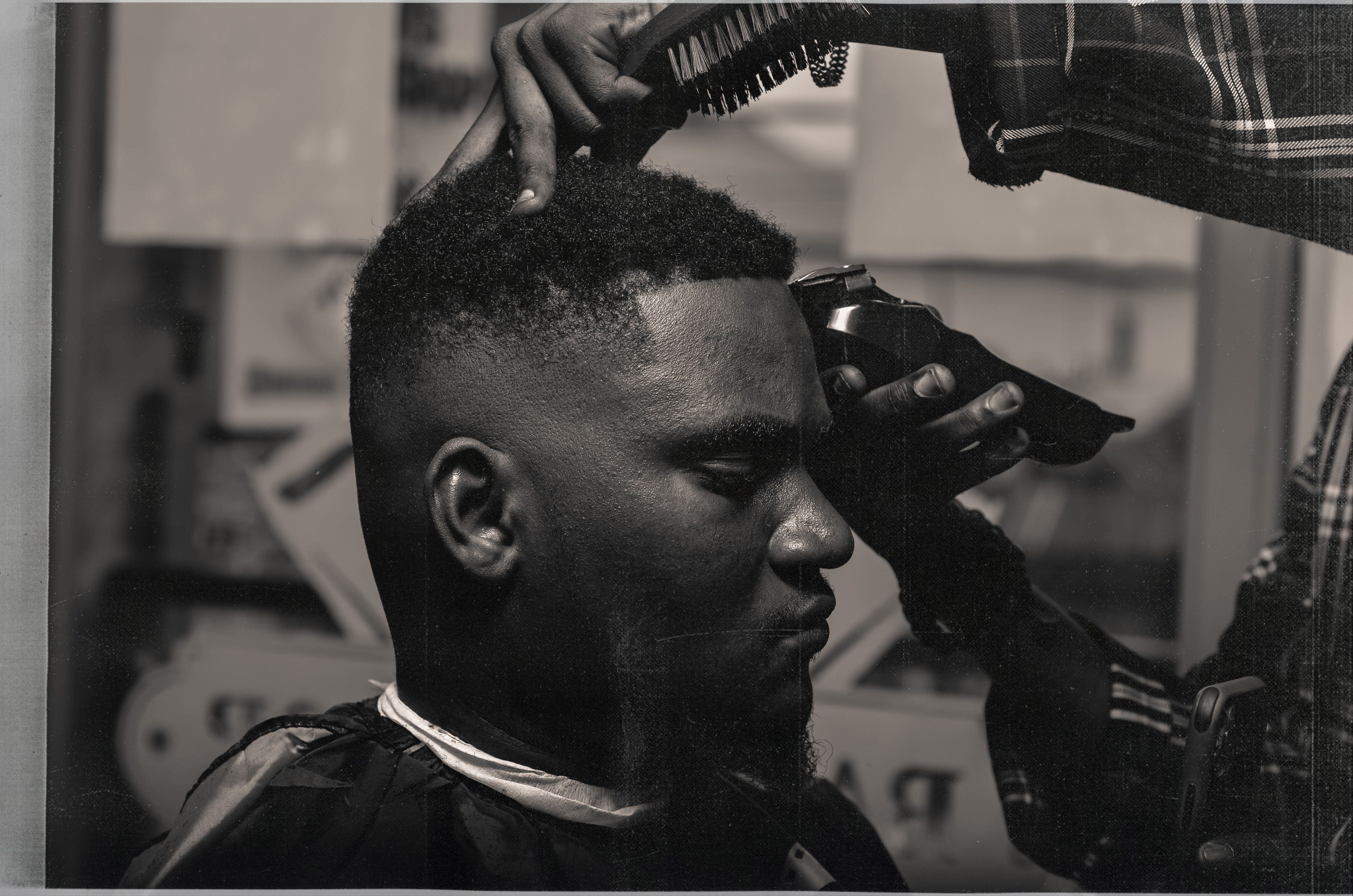 Barber working on a haircut and beard in the chair; concept style imagery
