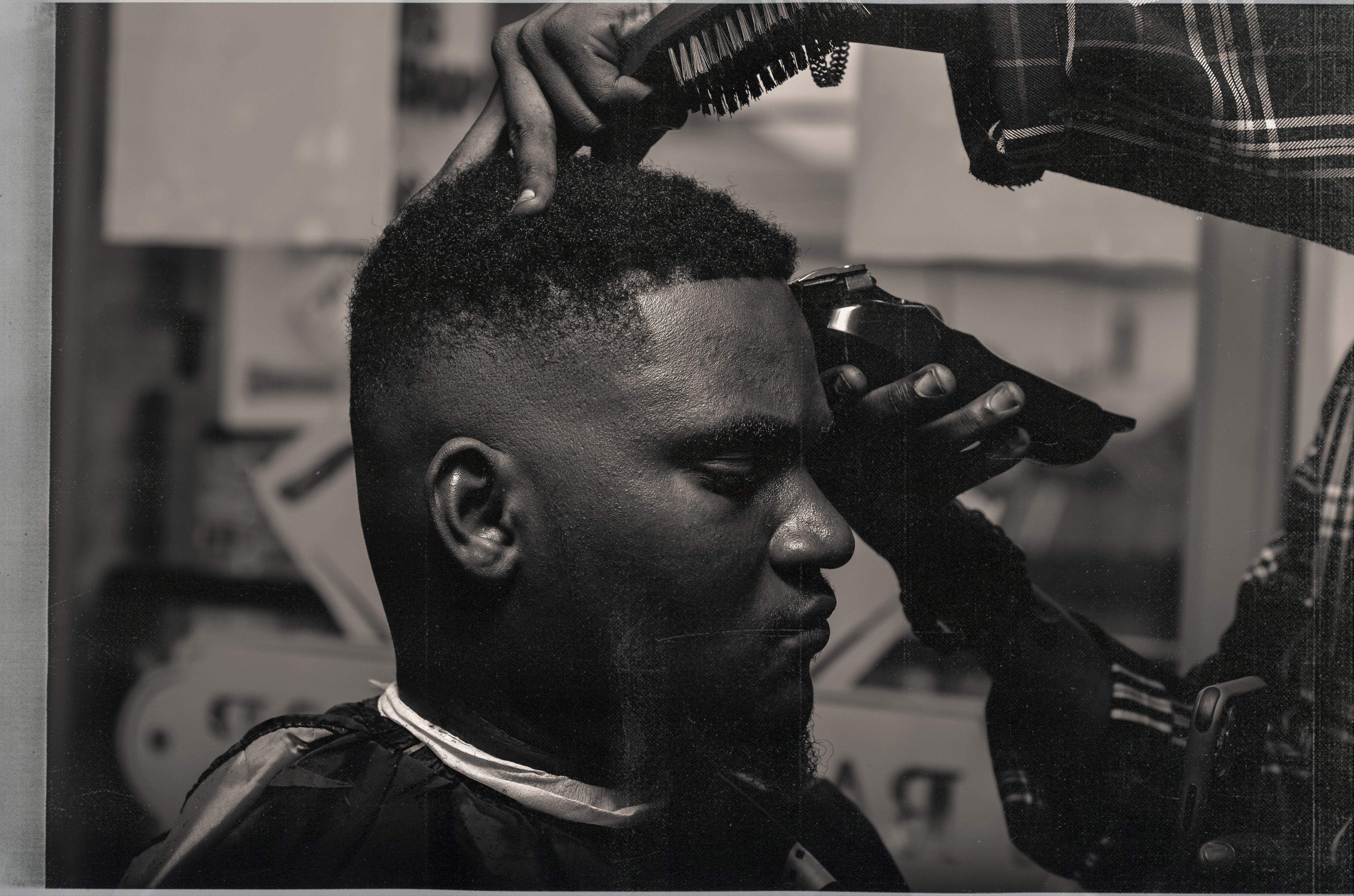 Barber working on a haircut and beard in the chair; concept style imagery