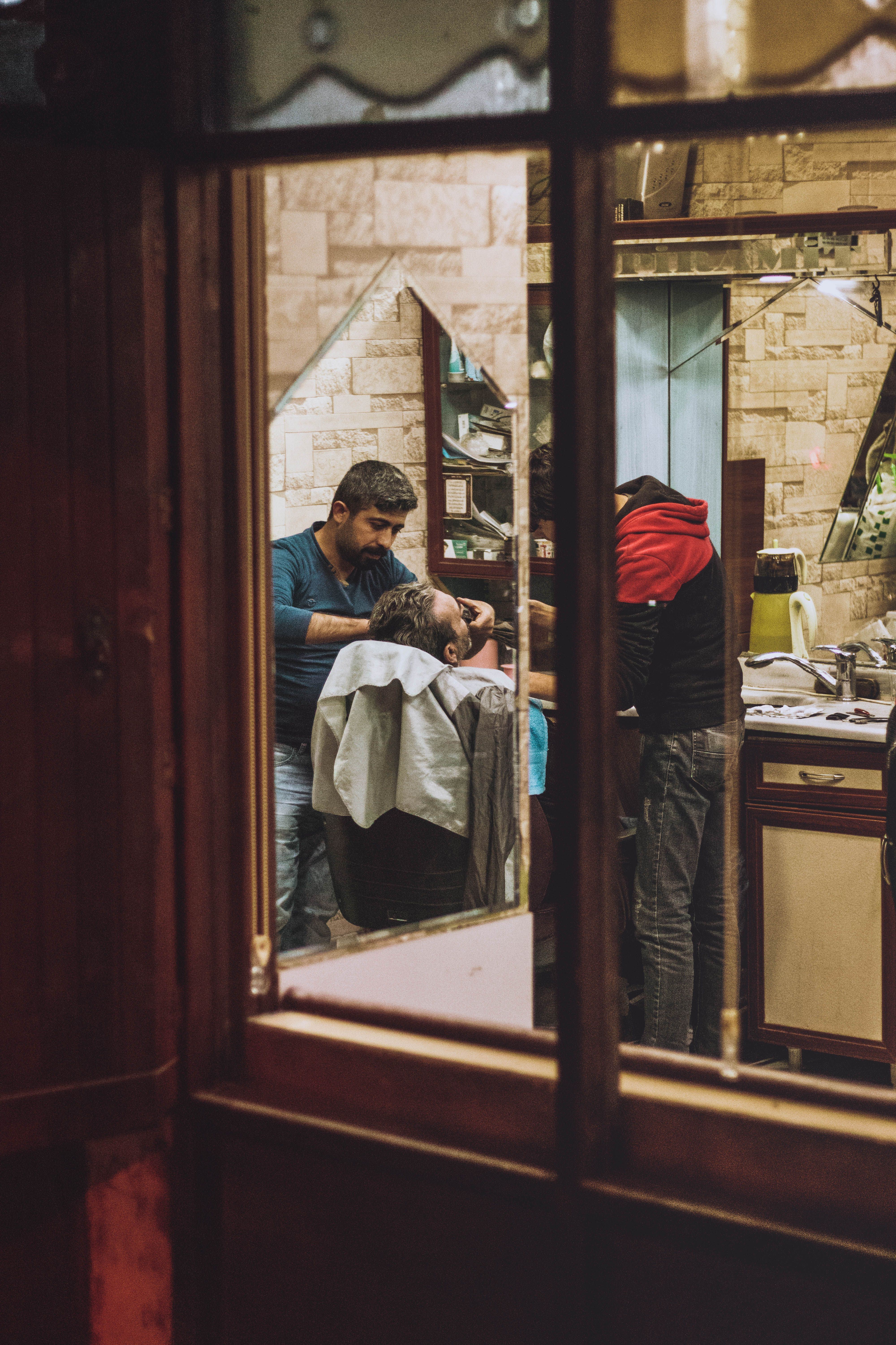 Barber shaping a client’s beard in the chair; concept style imagery