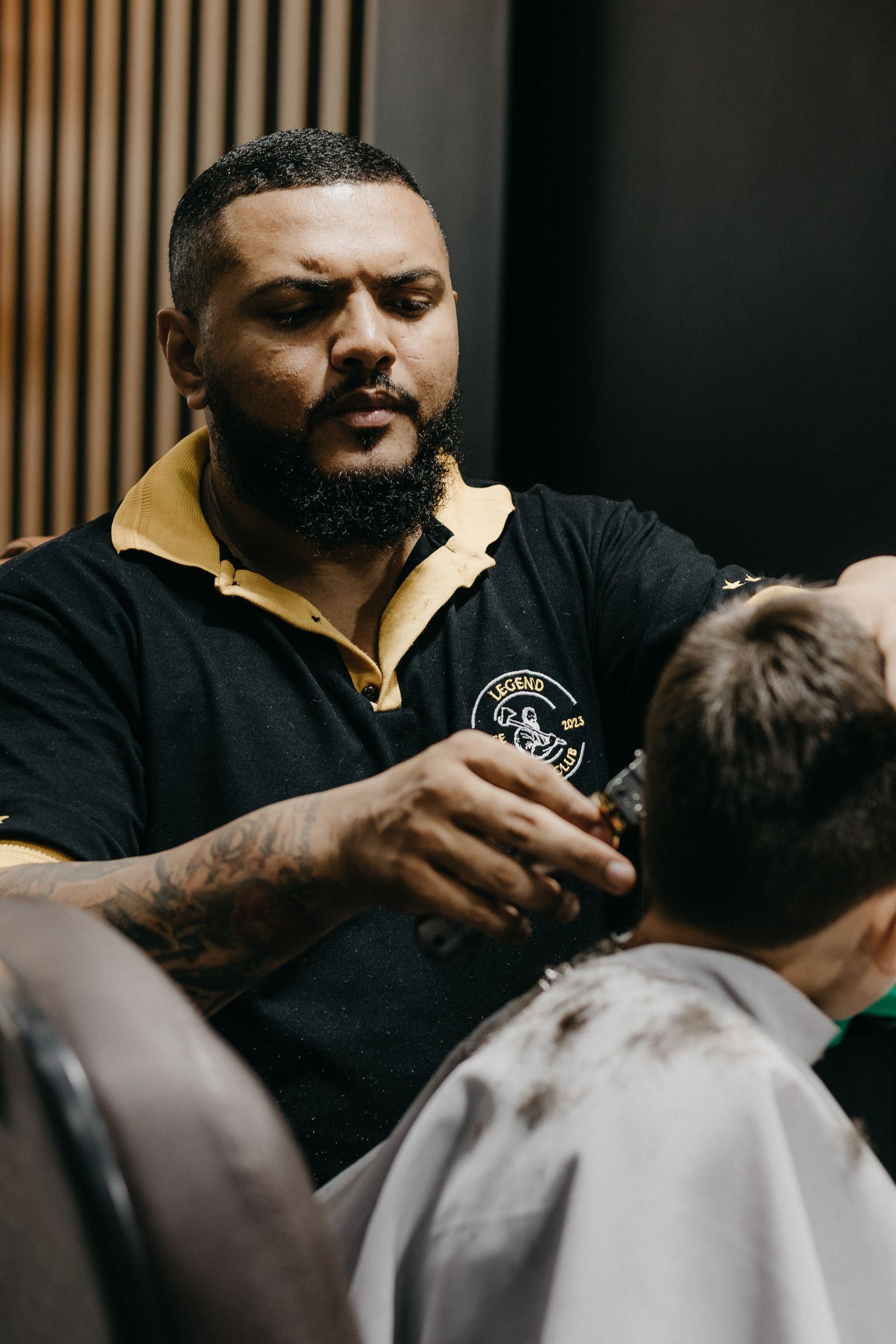 Barber giving a young client a careful haircut; concept style imagery
